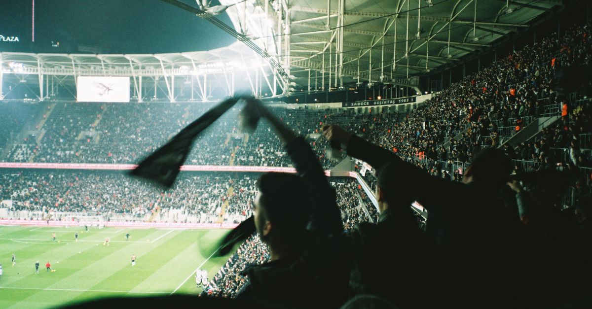 Exciting night soccer match with cheering fans in a brightly lit packed stadium.