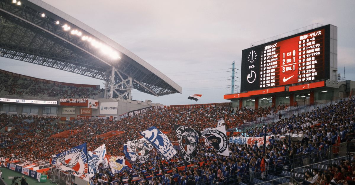 Energetic soccer match scene with cheering crowd and colorful flags in a large stadium.