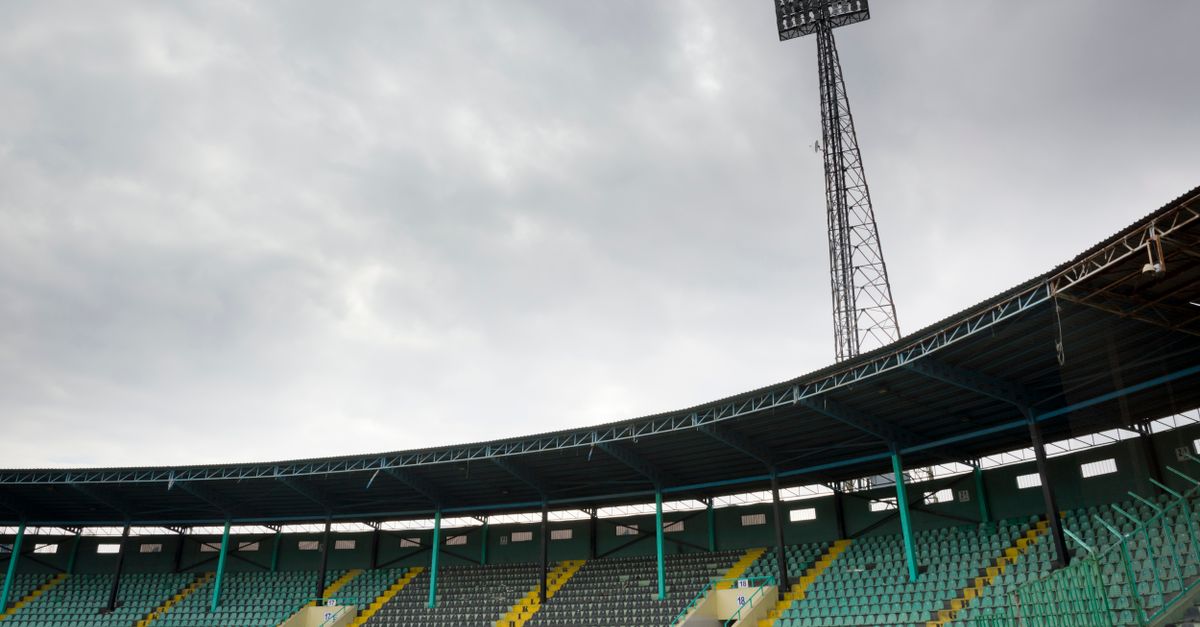 An empty soccer stadium with colorful seats under a cloudy sky, perfect for sports themes.