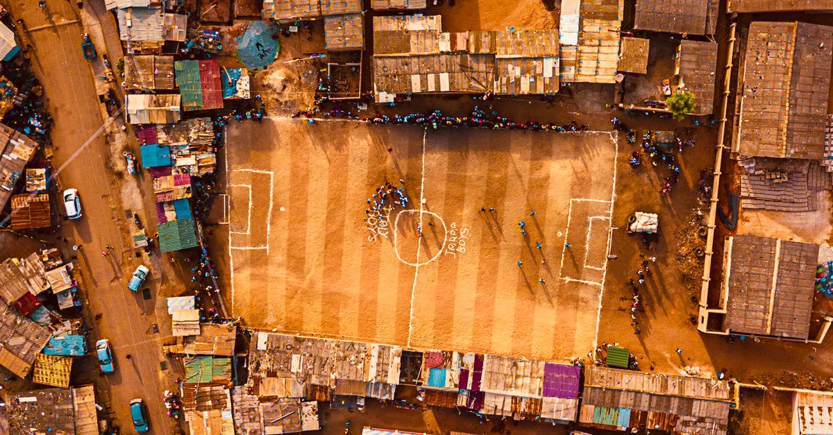 Aerial shot of an urban football field surrounded by dense housing in Accra, Ghana.